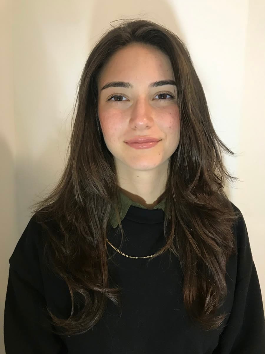 Burcu Payidarol, a young woman with dark hair in a black sweater, facing the camera on a white background